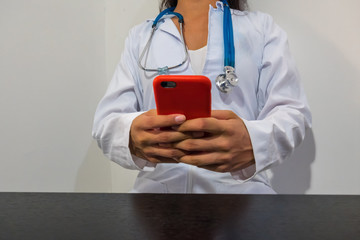 Doctor using smartphone on the table in the hospital room, telemedicine or videoconferencing, concept of electronic health record systems