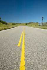 A yellow line down the center of old route 58, CA near an old windmill and farm