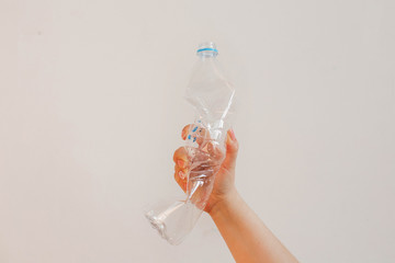 The concept of stopping plastic pollution, global warming, recycling plastic, without plastic. A hand clutching an empty transparent plastic bottle in protest. White background with isolated theme.
