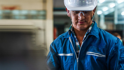 portrait of caucasian man industrial worker or labor in blue factory uniform with white safty helmet in factory metal workshop