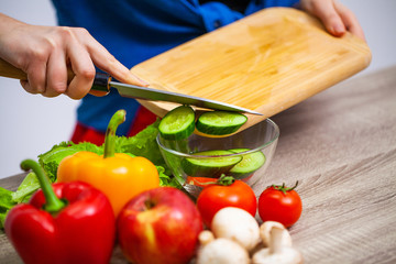 Closeup of woman slices cucumber for fresh salad