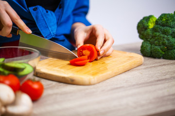 Closeup of woman slices tomato for fresh salad