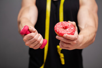 Athlete holding dumbbell and donut hint at workout.