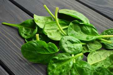Spinach leaves on dark wooden table background. Vegan food trend. Green living concept.