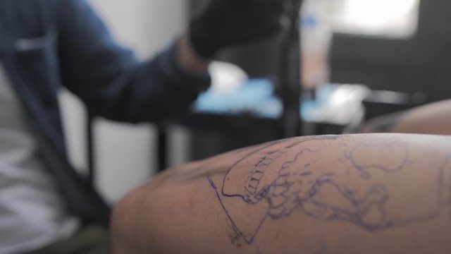 Close-Up of a Tattoo Artist Tattooing a skull on leg.
