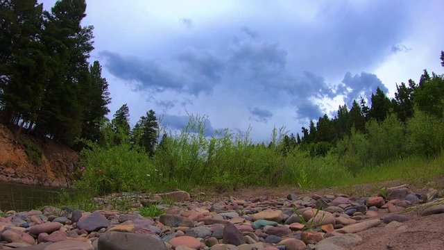 Time lapse of thunder clouds rolling in over a river.