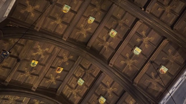 Arched wood paneled ceiling with heraldry and floral cruciform patterns.