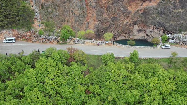 Tourists on road on top of cliff next to the red lake, Imotski, aerial fly over