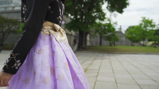 Married woman in traditional Korean hanbok walking in Gyeongbokgung Palace entrance, medium profile tracking shot in slow motion.