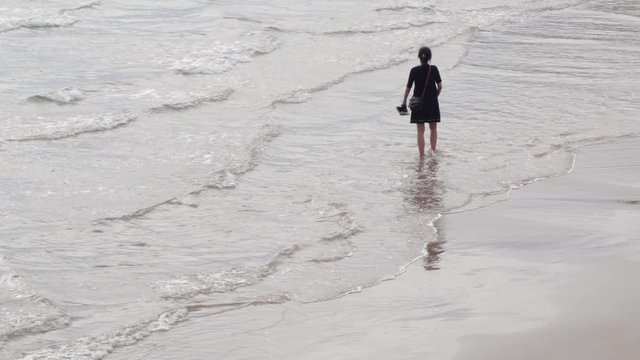 woman walking along the shore of the beach