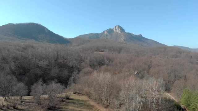 Aerial ascend above a deciduous forest revealing Klek mountain in north-western Croatia, near Ogulin