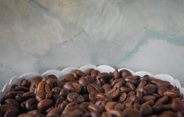 Arabica coffee beans roasted in a white basket, the background is a wall. The coffee background image has a text input area. Roasted coffee to keep the aroma good.