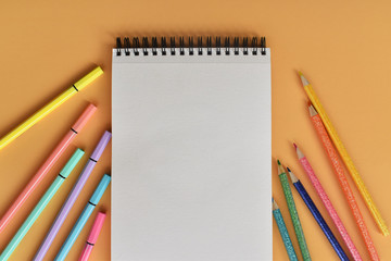 Libreta y colores sobre fondo color durazno