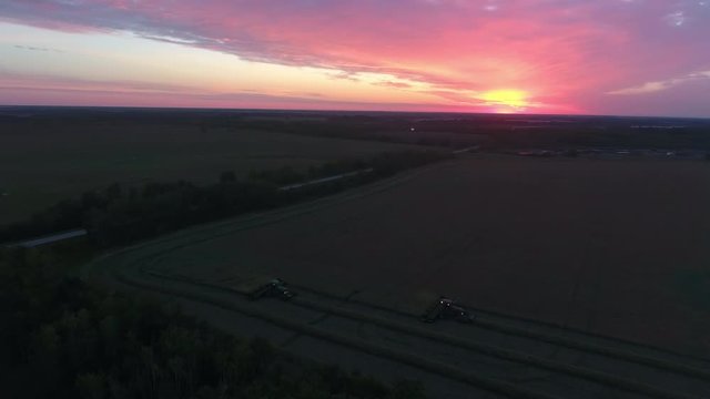 Drone shot of two swathers on a canola field during sunrise
