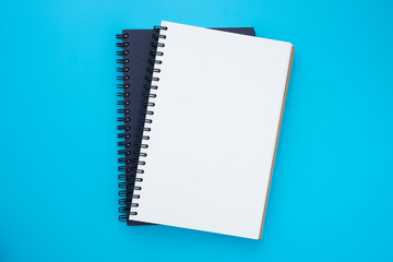 Top view above of two spiral notebooks that open and close, stacked isolated on light blue background for design a mockup. Education and business concept. flat lay