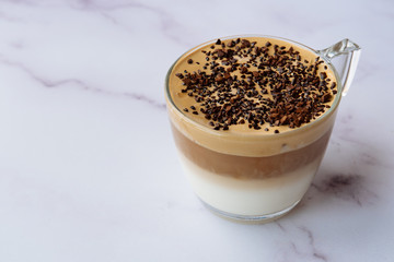 Dalgona coffee glass on a marble background. Korean drink. Soft, creamy and fluffy coffee