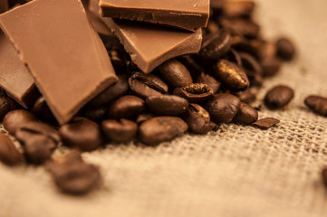 Pile of coffee beans with chocolate on burlap cloth background