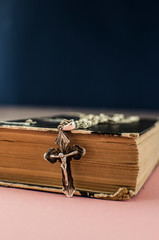 Close-up of a cross and a old Bible book. Christian background trust and faith concept with copy space