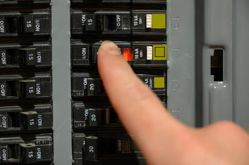 Finger resetting a tripped breaker in residential house electric box