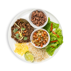 A plate of traditional Mexican minced beef served with bowls of with rice, beans and fresh tomato and coriander salsa with lime wedges