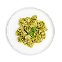 A plate of Spinach tortellini stuffed with ricotta in creamy pesto sauce served with grated parmesan cheese isolated on white