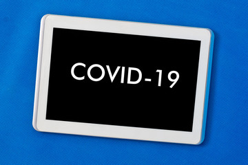 Tablet with the inscription covid-19 - The concept of online work during the coronavirus epidemic...