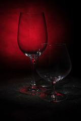 Two empty glass glasses against a dark background. Shot in a low key.