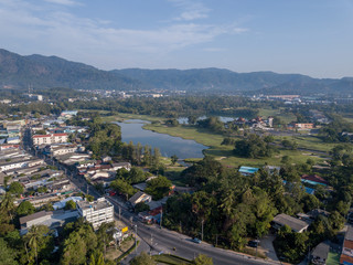 Beautiful lake located on a golf course surrounded by houses and mountains at dawn, photo from a drone. In the lake the reflection of the sky. Great background for travel and golf advertising.