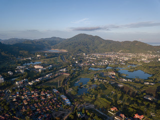 Beautiful lake located on a golf course surrounded by houses and mountains at dawn, photo from a drone. In the lake the reflection of the sky. Great background for travel and golf advertising.