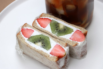 Strawberry and kiwi fruit with cream Sandwich and a glass of ice coffee in white round plate.