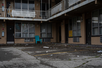 old abandoned motel with chair in the front and dirty and vandalized environment - obrazy, fototapety, plakaty