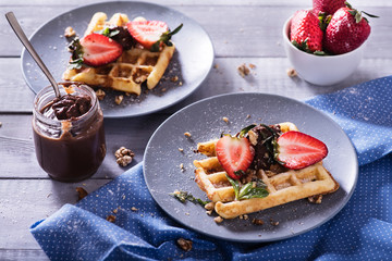 Two plates of Belgian waffles with chocolate sauce and fresh  strawberries on white background. Delicious sweet dessert.