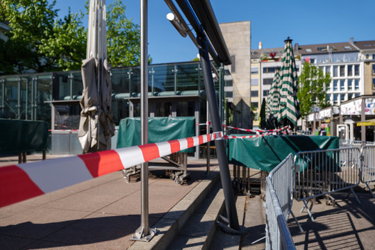 Red and white caution tape wrapped around outdoor eating area of cafe in Carlsplatz closed during global quarantine from COVID-19. Lockdown  and quarantine time in epidemic of COVID-19 Virus crisis.