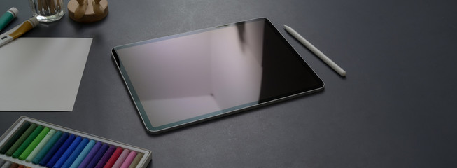 Cropped shot of dark concept office desk with digital tablet, stylus pen and designer supplies