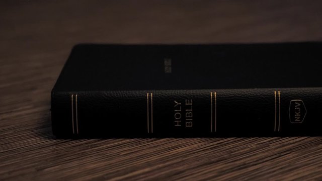 Pan Shot of Closed Holy Bible on Wooden Table