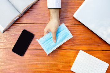 Protective face mask on wood table. Close up young asian business man, work from home.