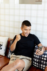 Young man stay at home In the COVID-19 situation, Which happily takes everyday life in your home on your favorite brown sofa She is currently working on a smart phone.