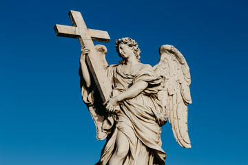 Naklejka premium Statue of Angel Holding Cross on bridge near st peter basilica rome italy