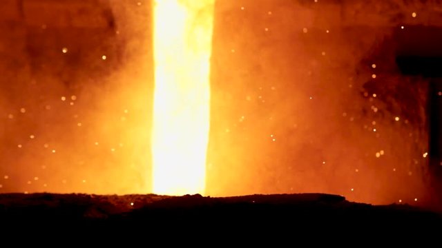 Molten metal being poured out of a crucible in a metal foundry.