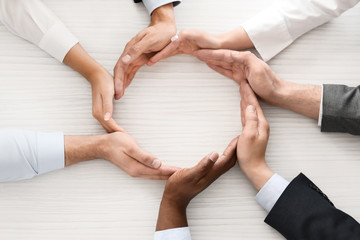 Group of business people making circle with their hands in office, top view. Unity concept