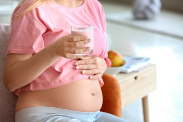 Beautiful young pregnant woman with yogurt at home