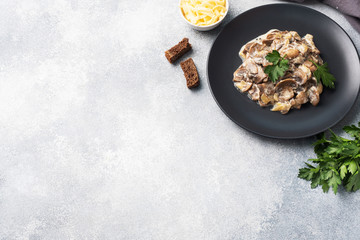 Stewed mushrooms champignons in sauce with sour cream and cheese parsley on a plate. Copy space.
