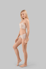 Fototapeta premium Young woman in underwear posing confidently, body care and wellness, healthy lifestyle, isolated on gray background