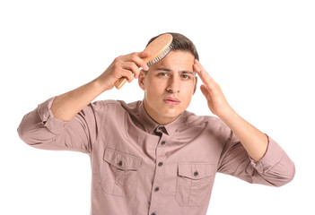 Fototapeta premium Handsome young man brushing hair on white background