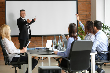 Mature businessman giving presentation during meeting in office