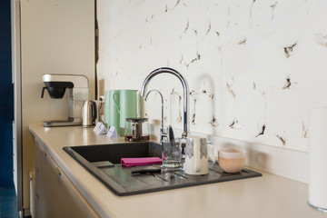 sink, faucet, cups and kettle with coffee machine in the office