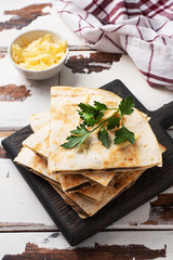 Pieces of quesadilla with mushrooms sour cream and cheese on a wooden stand with parsley leaves. Wooden background copy space.