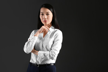 Portrait of young Asian businesswoman on dark background