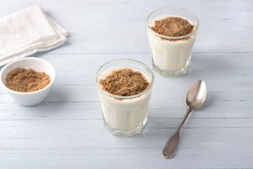 Simple healthy breakfast or snack. Natural yogurt with ground flax seeds in glasses on a light blue background