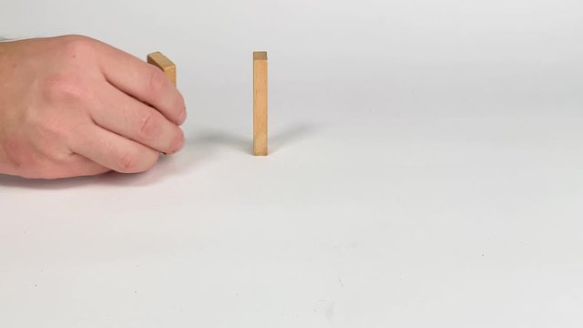 Man placing Jenga blocks for a chain reaction domino effect in slow motion
